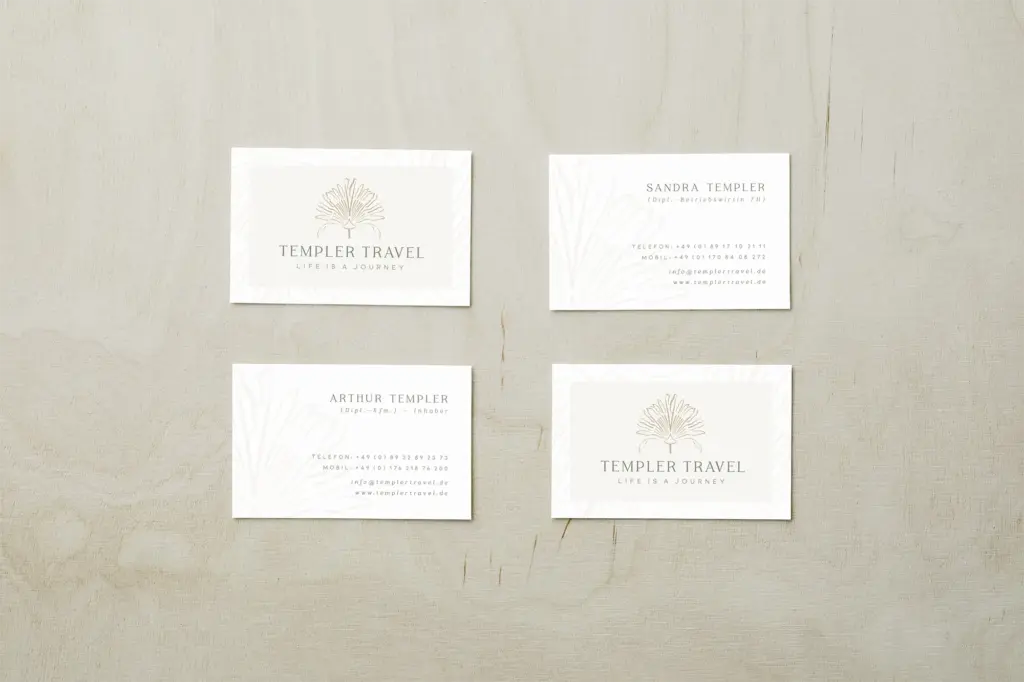 Vier weiße Visitenkarten für Templer Travel zeigen das minimalistische Blatt logodesign münchen und die Kontaktdaten, angeordnet auf einer hellen Holzoberfläche. Zwei Karten zeigen persönliche Informationen, zwei heben den Firmennamen und den Slogan hervor und spiegeln so ein raffiniertes Visual Branding wider.