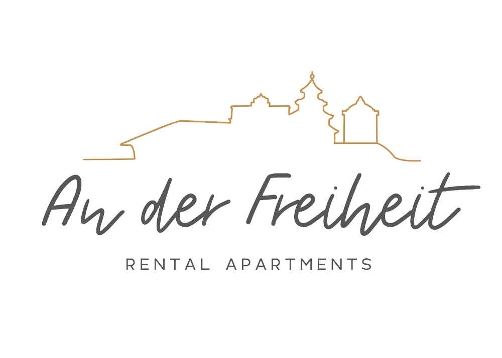 Logo für An der Freiheit Rental Apartments mit einer minimalistischen Linienzeichnung einer historischen Skyline über dem Text, mit Grau- und Goldtönen auf einem hellen Hintergrund. Perfekt für visuelles Branding und professionelles Logodesign München.
